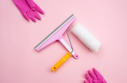 Window cleaning brush and roller for repair and rubber gloves on a pink background